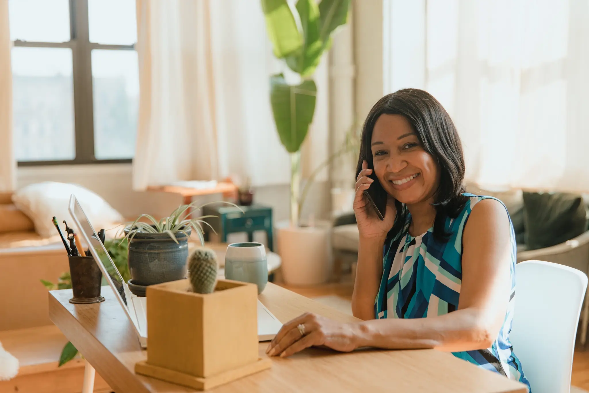 A woman smiling on the phone at her desk at home